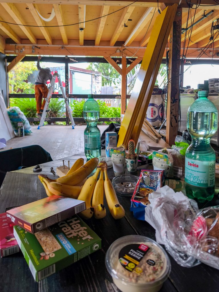 reUnion Innenansicht Bauarbeiten Oktober 2025 - im Vordergrund unser Tisch mit Vesper und Getränken, im Hintergrund Jakob, der auf einer Leiter steht